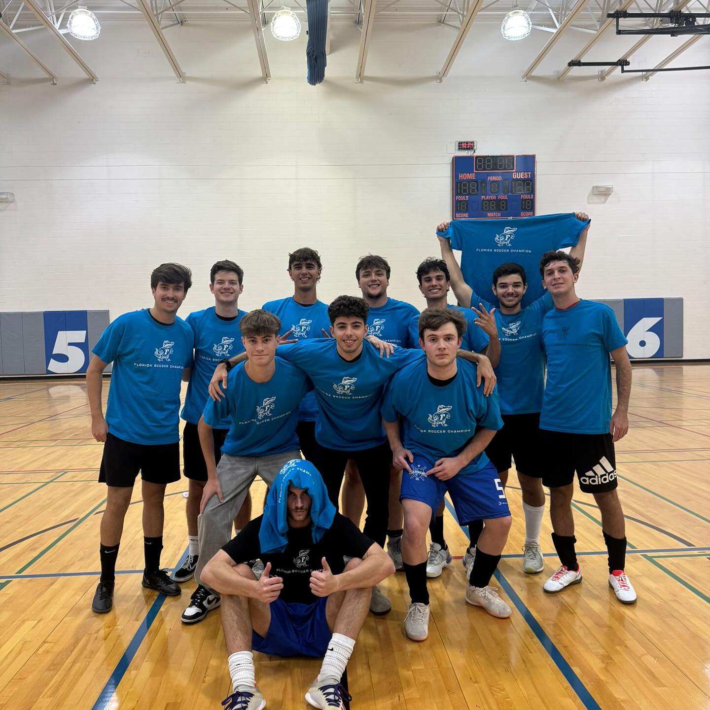 Indoor soccer team in blue shirts posing in a UF gym