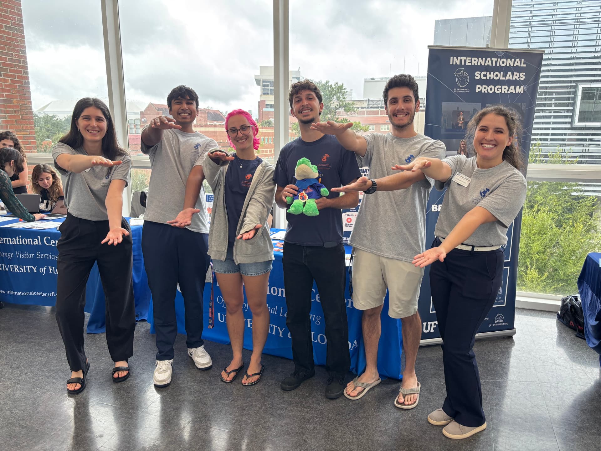 Rafael and International Center colleagues posing beside an International Scholars Program banner