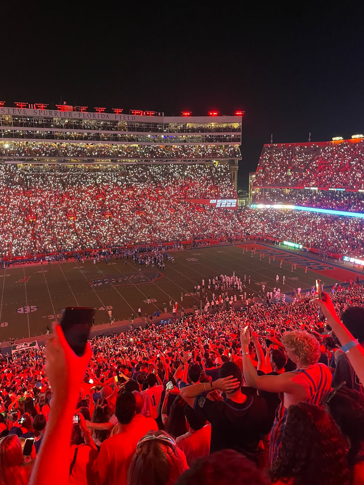A packed UF football stadium at night, lit in red