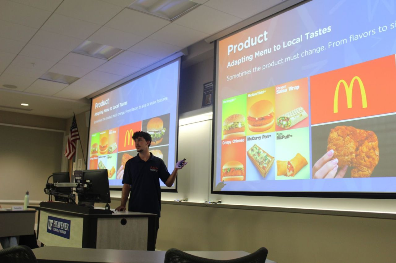 Rafael presenting slides on adapting menus to local tastes in a UF Heavener School of Business classroom